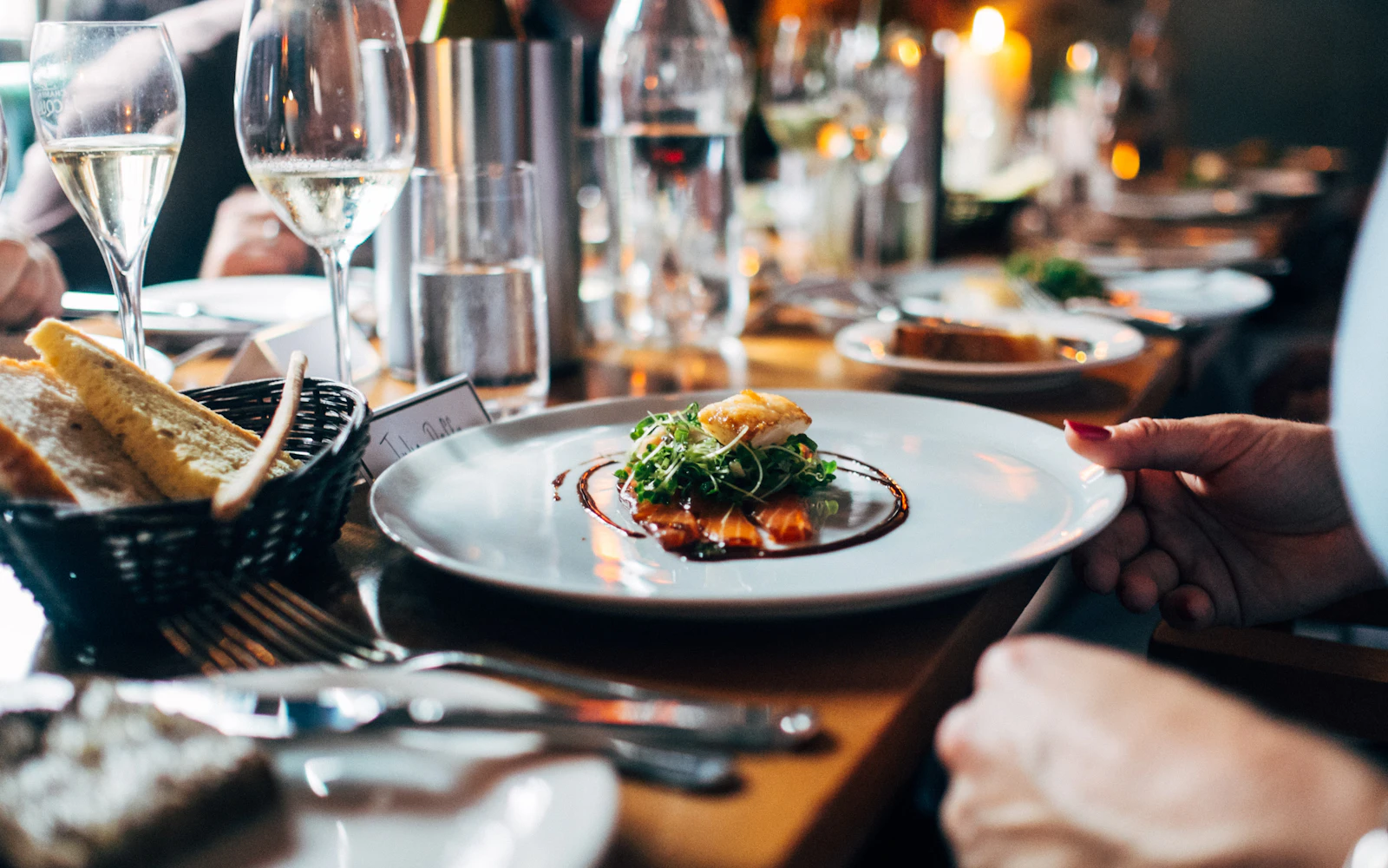 A plated dish being served at a candlelit dining table